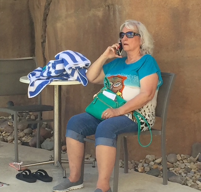 Linda wearing sunglasses and a turquoise shirt, seated beside a striped towel.