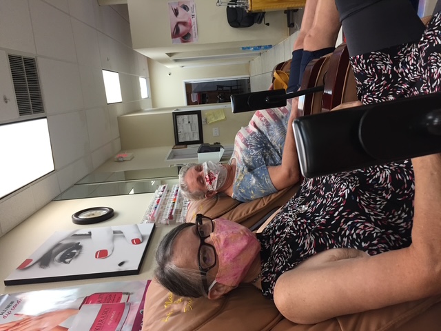 Linda and a woman sitting together, both wearing face masks.