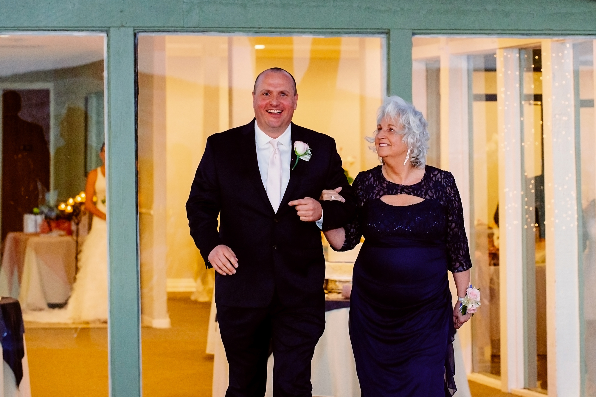 Jason and Linda walking arm in arm through a doorway on his wedding day.