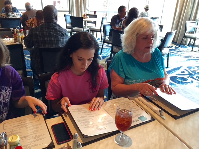 Linda and a girl looking at menus side by side at a restaurant table.