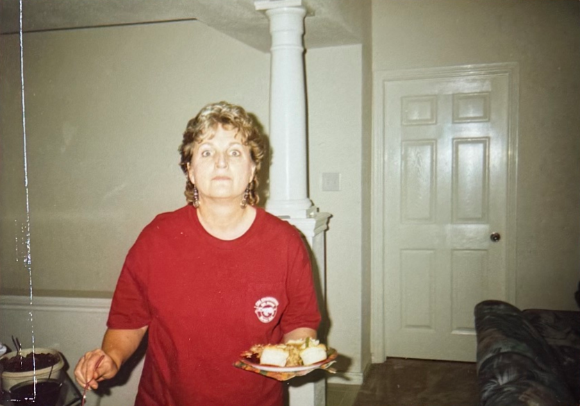 Linda in a red shirt, holding a plate of dessert at home.