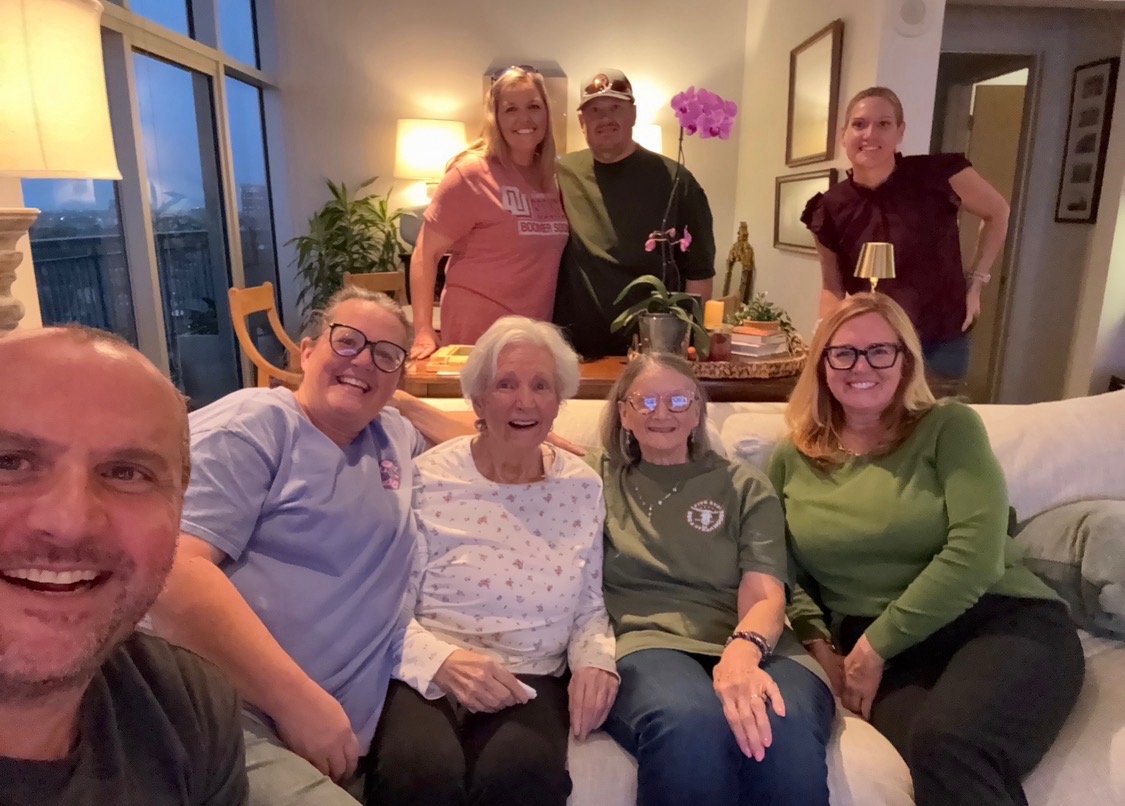 A group gathered around Linda on a sofa, smiling for a family photo.