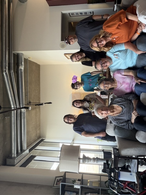 A group gathered for a photo in a garage, with Linda seated in front.