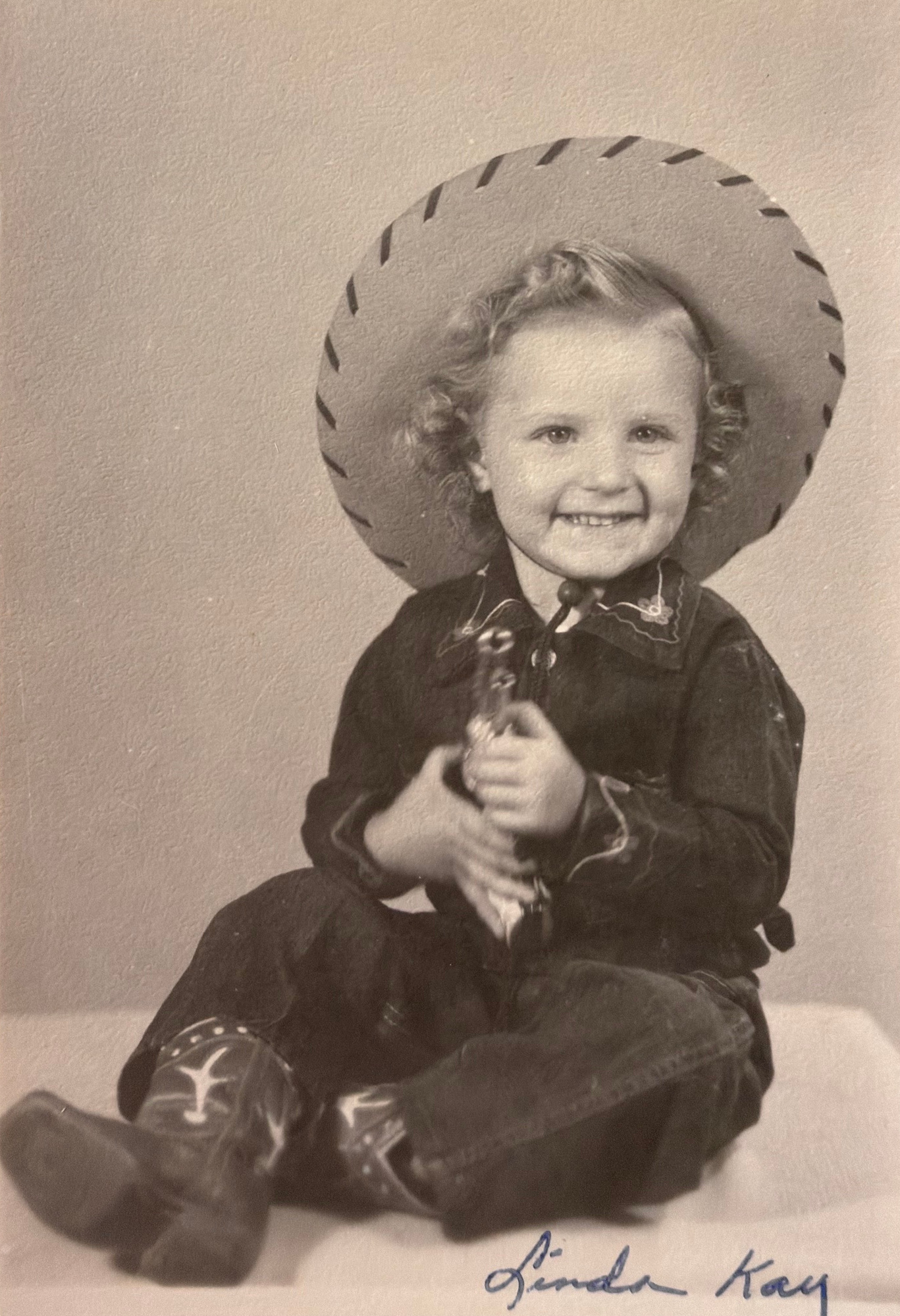 Linda as a little girl in a cowboy hat and boots, with Linda Kay handwritten at the bottom.