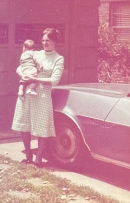 Linda holding Jason as a baby, standing beside a car in May 1975.