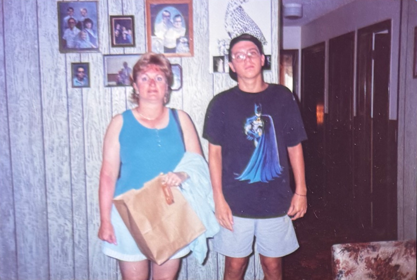 Linda and a young man standing together indoors.